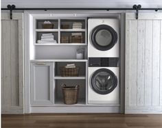 a washer and dryer sitting in a room next to some shelves with baskets