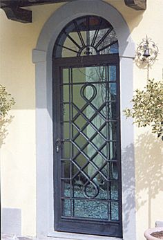 the front door to a house with an iron gate and decorative glass window above it