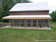 an enclosed area with several animals in it and a barn behind the fenced off area