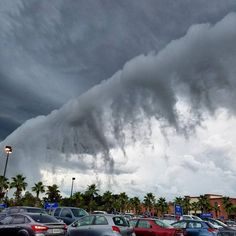 a very large cloud is in the sky over a parking lot