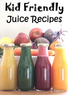 three bottles of juice sitting on top of a table next to some fruit and vegetables