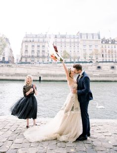 a bride and groom kissing in front of the seine river with their arms in the air