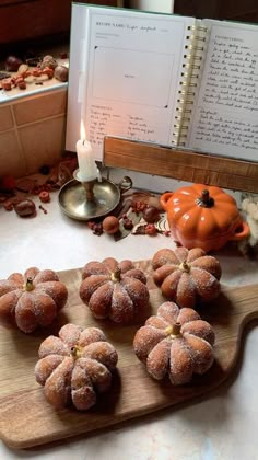 several donuts are arranged on a wooden board next to a candle and recipe book