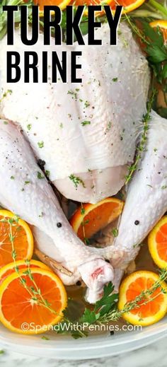 a whole chicken in a plastic container surrounded by oranges and herbs