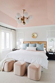 a bedroom with pink walls and white bedding, two foot stools on the floor