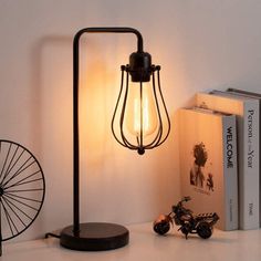 a lamp that is on top of a table next to some books and a bike