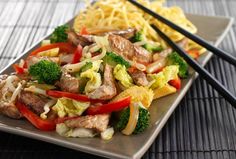 a plate filled with meat and veggies next to chopsticks on a table