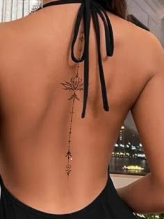 the back of a woman's body with tattoos on it, and an arrow