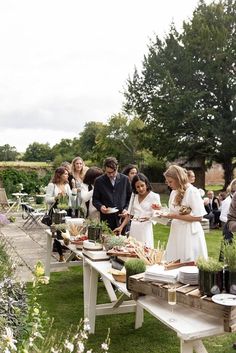 a group of people standing around a table with food on it