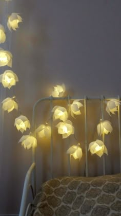 a crib with some lights hanging from it's sides and flowers on the bed