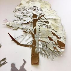 a paper cut out of a tree with people standing next to it on the wall