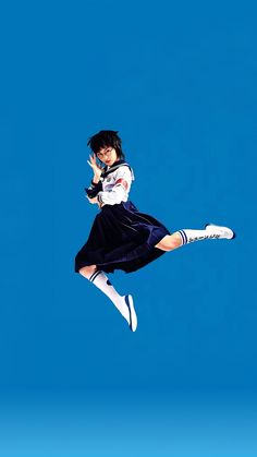 a woman is flying through the air while wearing a skirt and white shirt with blue socks