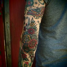 a man with a tattoo on his arm and flowers in the middle of his arm