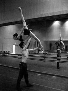 three men doing acrobatic tricks in an empty room with lights on the ceiling