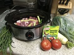 some vegetables and meat in a crock pot on a kitchen counter next to a bag of frozen soup