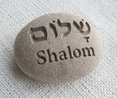 a stone with the word shalohm written on it sitting on a white cloth