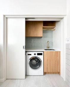 a washer and dryer in a small room with wooden cabinets on the wall