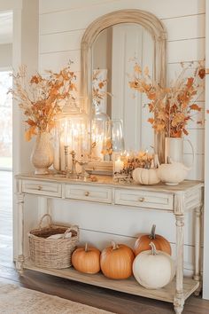 a white table topped with lots of pumpkins and other decorating items next to a mirror