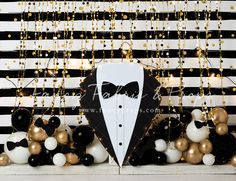 a black and white striped backdrop with balloons, bow tie and tuxedo sign