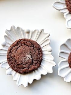 three chocolate cookies sitting on top of each other next to white paper plates with flower designs