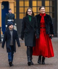 two women and a young boy walking down the street in front of an old building