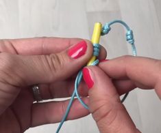 two hands holding blue and yellow string with beads