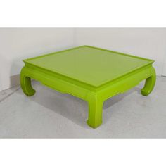 a bright green coffee table sitting on top of a white floor next to a wall