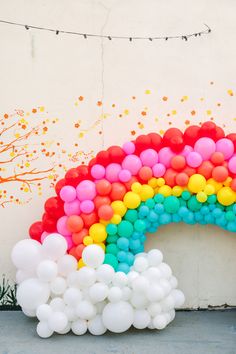 a rainbow shaped balloon arch in front of a painted wall