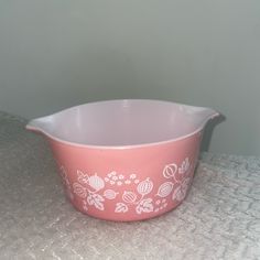 a pink casserole dish with white flowers on it