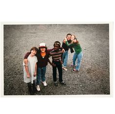 a group of people standing next to each other on top of a dirt field with one person giving the thumbs up