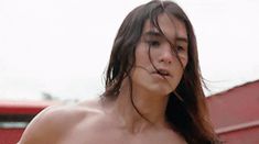 a shirtless man with long hair and no shirt holding a frisbee in his hand