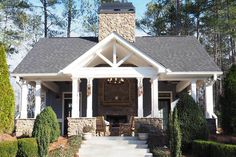 a house with stone pillars and white trim on the front door is surrounded by greenery