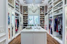 a walk - in closet with chandelier and lots of clothes on the shelves