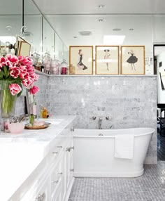 a white bath tub sitting inside of a bathroom next to a sink and toilet covered in pink flowers