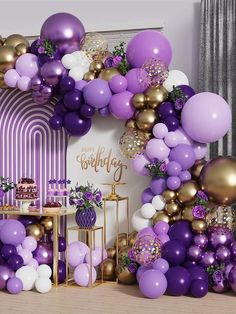 a purple and gold party with balloons on the wall