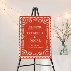 an easel with a welcome sign on it in front of a string of lights