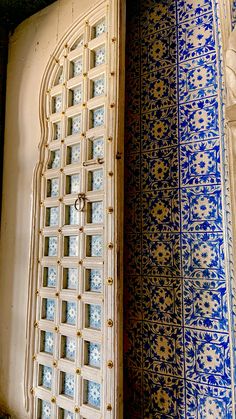 an ornate door with blue and white tiles on the outside, in front of a wall