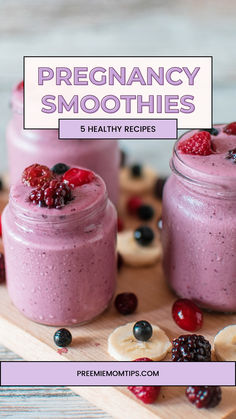 two jars filled with smoothies on top of a cutting board next to bananas and raspberries