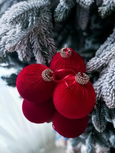 three red ornaments are hanging from a christmas tree