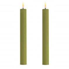 two green candles with one lit and the other turned on, in front of a white background