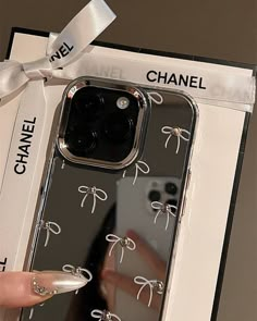 a woman holding up her phone case with bows on the front and back cover, in a box