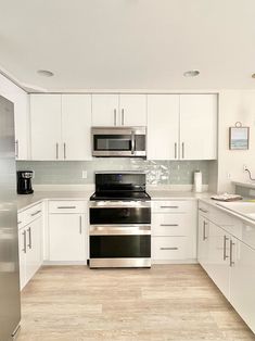 an empty kitchen with white cabinets and stainless steel appliances, is pictured in this image