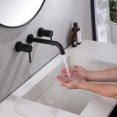 a person washing their hands under a faucet