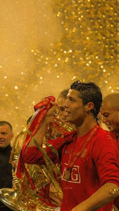 two men in red shirts standing next to each other and holding a silver tray with gold confetti on it