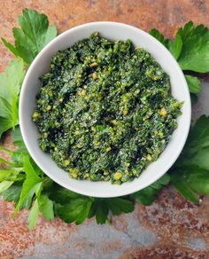 a white bowl filled with greens on top of a table