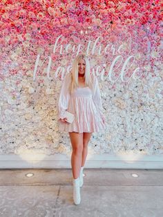 a woman standing in front of a flower wall