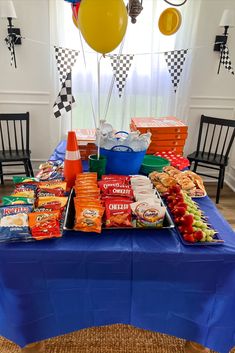 a blue table topped with lots of food and balloons