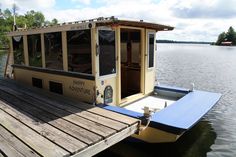 a house boat docked at the end of a pier with its door open to let people in