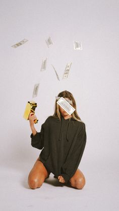 a woman sitting on the floor with money falling from her eyes and reading a book