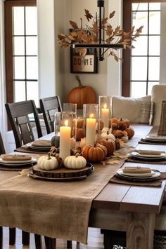 a dining room table with candles and pumpkins on it